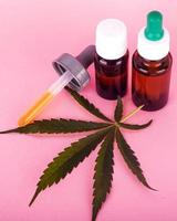 hennepolie voor medisch gebruik, flessen met medicinaal cannabisextract op roze achtergrond foto