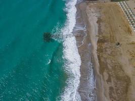 antenne visie van zee crashen golven wit schuimend golven Aan kust rotsen top visie foto