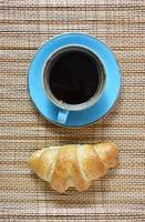 koffiekopje en verse croissant geïsoleerd op vintage gestructureerde bruine achtergrond. bovenaanzicht op vers ontbijt met koffie en gebakken zoete gebakjes. foto