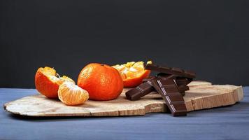 mandarijnen met zwarte chocolade op houten standaard op een donkergrijze achtergrond foto