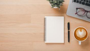 kantoor houten bureau werkplaats met laptop computer, notitieboekje, pen en kop van koffie, top visie vlak leggen met kopiëren ruimte. foto