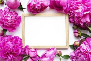 houten frame omgeven door mooie roze pioenrozen op een witte achtergrond foto