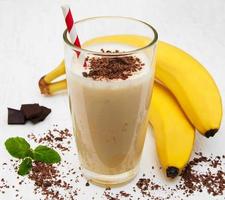 banaan smoothie met chocolade op een oude witte houten achtergrond foto