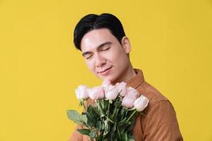 jong Aziatisch Mens Holding bloem Aan achtergrond foto