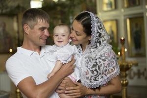 familie met baby in kerk. ouders met een kind in een orthodox kerk foto