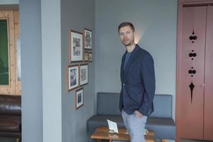 Mens met handen in zakken staand door muur Bij luxe hotel foto