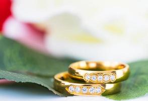 dichtbij omhoog goud ring en rood rozen Aan wit foto