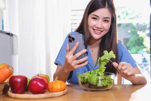 eetpatroon, witte huid jong Aziatisch vrouw in een blauw overhemd aan het eten groente salade en appels net zo een gezond eetpatroon, kiezen voor rommel voedsel. vrouw voedingsdeskundige verliezende gewicht. gezond aan het eten concept. foto