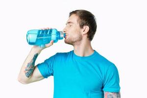 vent atleet drankjes water van een fles Aan een wit achtergrond en een blauw t-shirt foto