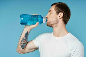 Mens drinken water van blauw fles geschiktheid training dorst foto