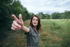 vrouw portret Aan natuur ogen gesloten, tonen vers lucht met een vinger foto