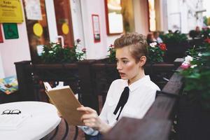 leerling met een boek in zijn handen buitenshuis in een zomer cafe rust uit communicatie foto