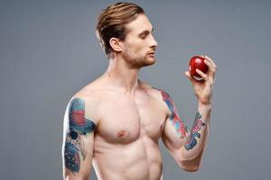 atletisch Mens met een opgewonden torso en een tatoeëren Aan zijn arm rood appel Gezondheid foto