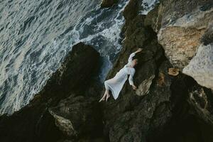 mooi jong vrouw in wit bruiloft jurk Aan zee kust nat haar- landschap foto
