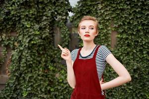 mooi vrouw met kort haar- Aan de straat tegen de achtergrond van struiken foto