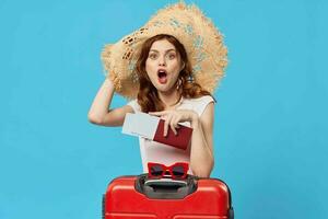 vrouw met rood koffer zittend Aan de verdieping blauw achtergrond reizen vakantie foto