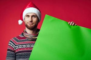 emotioneel Mens in een Kerstmis hoed met groen mockup rood achtergrond foto