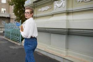 kort haren vrouw met bril wandelen in de omgeving van de stad met een boek onderwijs foto