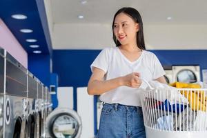 jong Aziatisch vrouw met gekruld haar- glimlachen gelukkig aan het doen klusjes Bij de wasserij foto