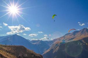 paragliders en toeristen op bergen met zonnevlam foto