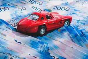 rood speelgoed- auto Aan een stapel van geld. Russisch 2000 roebels. verzekering, credit, lening. foto