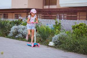 kind rijden scooter. kind Aan kleurrijk trap bord. actief buitenshuis pret voor kinderen. zomer sport- voor peuter- kinderen. foto