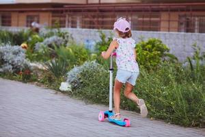 kind rijden scooter. kind Aan kleurrijk trap bord. actief buitenshuis pret voor kinderen. zomer sport- voor peuter- kinderen. foto