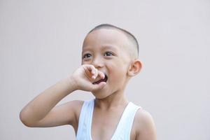 Aziatisch jongen zetten zijn vinger in zijn mond foto