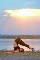 jong meisje aan het doen yoga geschiktheid oefening ochtend- zonsopkomst buitenshuis in de weide mooi bergen landschap. meditatie en kom tot rust. foto