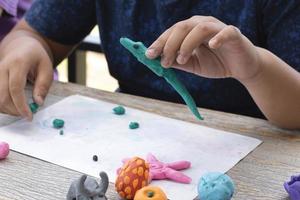 een autistisch jongen gieten verschillend vormen van gekleurde plasticine bereid door ouders Bij huis in bestellen naar ontwikkelen divers aspecten in hun zoon welke heeft langzamer hersenen ontwikkeling dan normaal kinderen. foto