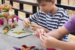 een autistisch jongen gieten verschillend vormen van gekleurde plasticine bereid door ouders Bij huis in bestellen naar ontwikkelen divers aspecten in hun zoon welke heeft langzamer hersenen ontwikkeling dan normaal kinderen. foto