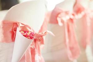 mooi roze roos bloemblaadjes bloemen met roze lint decoratie Aan stoelen in bruiloft evenement hal. foto