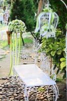 wit vogelkooi, stoel decoratie met rozen en wit bloemen hangende decoratie in tuin voor bruiloft ceremonie foto