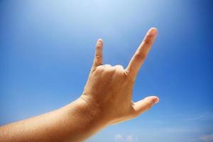 hand- teken van liefde en tonen vingers middelen ik liefde u Aan blauw lucht met zonlicht en kopie ruimte. foto
