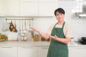 portret van slim jong Aziatisch Mens glimlachen in keuken Bij huis foto