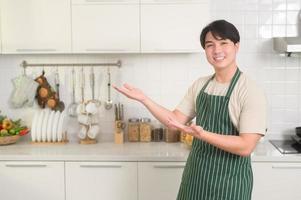 portret van slim jong Aziatisch Mens glimlachen in keuken Bij huis foto