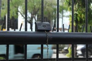 Jakarta, Indonesië - april 10e, 2023 - klein voorwerp Aan zwart hek met openbaar weg buitenshuis achtergrond, met metaal ijzer keten op slot doen. foto