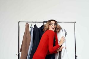 mooi vrouw in een rood jasje in de buurt de garderobe kleinhandel geïsoleerd achtergrond foto