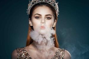 vrouw met een kroon Aan haar hoofd rook van de mond aantrekkingskracht luxe donker achtergrond foto