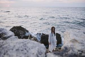 vrouw in wit jurk met nat haar- Aan de oceaan stenen ongewijzigd foto