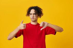 ontevreden grappig Kaukasisch jong Mens in rood t-shirt tonen dis Leuk vinden gebaar poseren geïsoleerd Aan geel studio achtergrond. de het beste aanbod met vrij plaats voor reclame. emoties voor elke dag concept foto