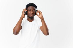 Mens van Afrikaanse uiterlijk in wit t-shirt luistert naar muziek- met hoofdtelefoons in technologie foto