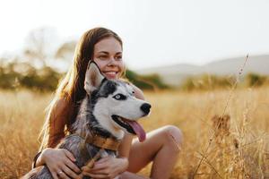 vrouw en haar schor hond gelukkig wandeling door de gras in de park glimlach met tanden vallen zonsondergang wandelen met huisdier, reizen met een hond vriend foto