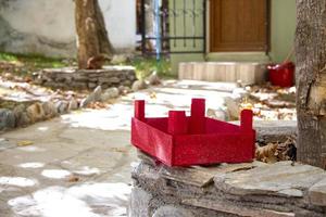 rood houten mand Aan een steen in de tuin. de rood houten doos Aan een steen muur in de binnenplaats van de huis foto