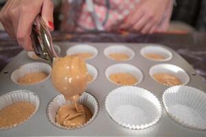 vrouw gieten mengsel van ingrediënten op bakplaat om muffins te maken foto