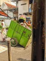 soera, Indonesië - april, 2023 - een dustman wie gooit vuilnis in de uitschot kar foto