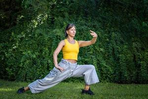 mooi vrouw geniet oefenen tai chi. vrouw combineert de praktijk van chi kung en Chinese krijgshaftig kunsten in een natuurlijk instelling naar verbeteren zijn praktijk en zijn verbinding naar de energie van natuur. foto