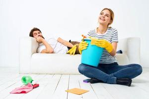 de man leugens Aan de bankstel terwijl zijn vrouw reinigt omhoog de interieur werk foto