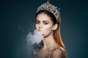 vrouw met een kroon Aan haar hoofd rook van de mond aantrekkingskracht luxe donker achtergrond foto