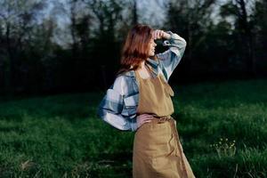 vrouw boerderij arbeider in schort ontspannende in natuur en aan het kijken de zonsondergang na een dag van werk Aan de boerderij foto